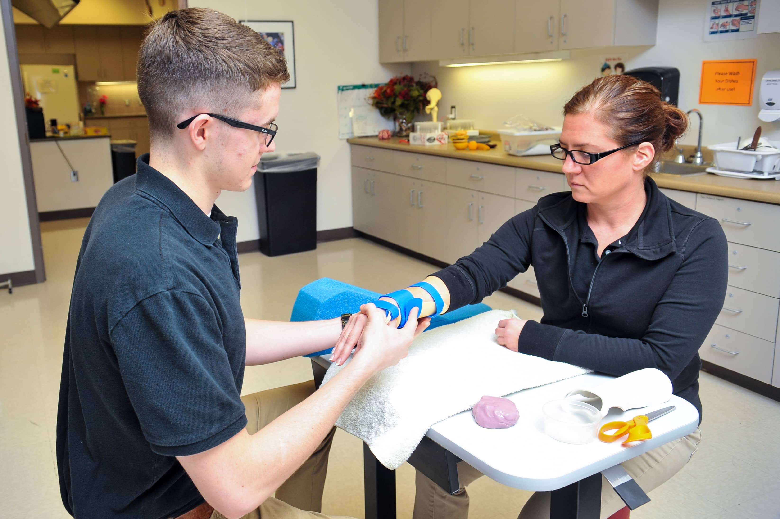 student setting woman's arm in brace